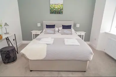 a bedroom with a large bed with two tables at The Mila - Ayr Racecourse - Coorie Doon Stays in Ayr