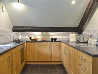 a kitchen with wooden cabinets and a black counter top at The Mill in Mungrisdale