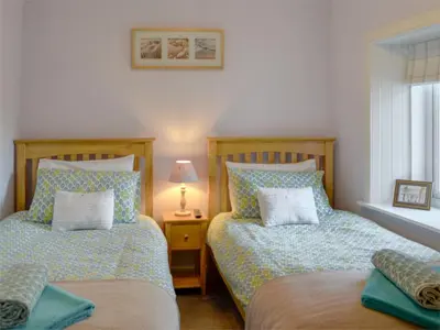 two beds sitting next to each other in a bedroom at River Cottage in Bladnoch