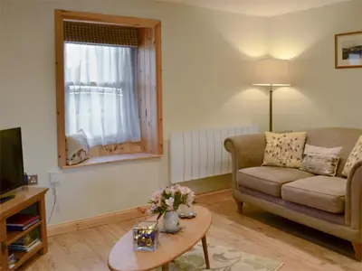 a living room with a couch and a table at River Cottage in Bladnoch
