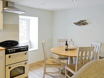 a kitchen and dining room with a table and a stove at River Cottage in Bladnoch