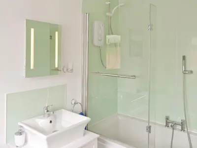 a white bathroom with a sink and a shower at River Cottage in Bladnoch