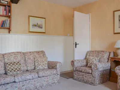 a living room with a couch and a chair at Old Saddlers Cottage in Ireby
