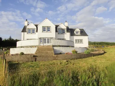 a large white house sitting on top of a field at Knockinaam House in Colfin