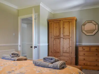 a bedroom with a wooden cabinet and two pillows on a bed at Fieldside Farmhouse in Tallentire