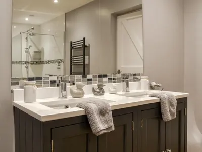 a bathroom with a sink and a large mirror at Fieldside Farmhouse in Tallentire