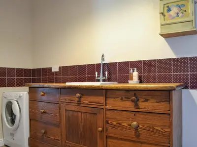 a kitchen with a sink and a washing machine at Fieldside Farmhouse in Tallentire