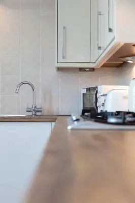 a kitchen with white cabinets and a sink at London Gate No1 - Donnini Apartments in Kilmarnock