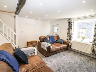 a living room with two leather couches and a window at Sparrow Cottage in Keswick
