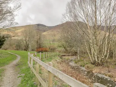 a wooden fence next to a dirt road at Sparrow Cottage in Keswick