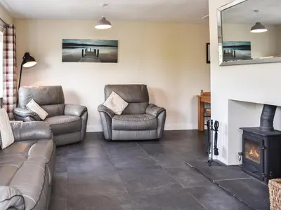 a living room with two chairs and a fireplace at Rosedean in Ireby