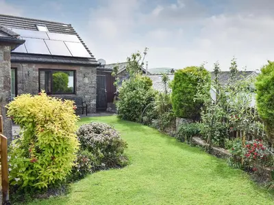 a garden with a house with a grass yard at Rosedean in Ireby