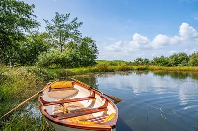 a wooden boat sitting on the side of a river at The Steading at Castle Creavie Farm in Kirkcudbright