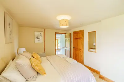 a bedroom with a large bed with white sheets at The Steading at Castle Creavie Farm in Kirkcudbright