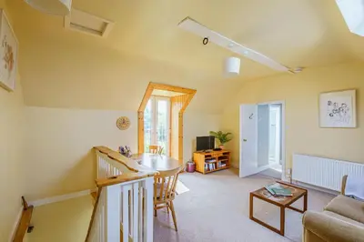 a living room with a table and a couch at The Cheeseloft - Spacious one bed with terrace in Kirkcudbright
