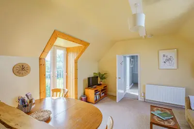 a dining room with a table and a television at The Cheeseloft - Spacious one bed with terrace in Kirkcudbright