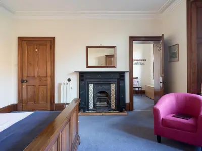 a bedroom with a fireplace and a pink chair at Yewthwaite Newlands Keswick in Keswick
