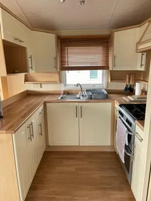 a kitchen with white cabinets and a sink at Beautiful 2-Bed Static caravan in Newton Stewart