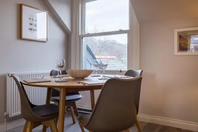 a dining room table with wine glasses and a window at Howe Keld 4 First floor in Keswick