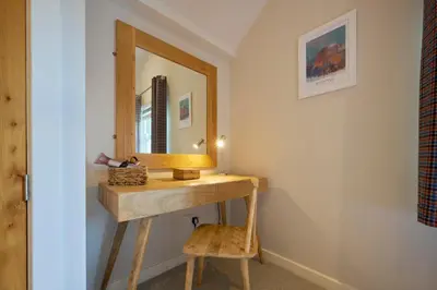 a bathroom with a vanity with a mirror and a stool at Howe Keld 5 First Floor in Keswick