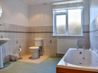 a bathroom with a tub and a toilet and a window at Littlethwaite in Keswick