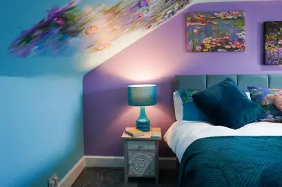 a bedroom with purple walls and a bed with a lamp at The Art Bank in Dalbeattie