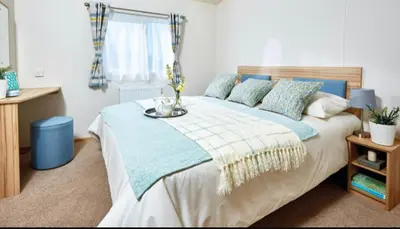 a bedroom with a large bed with a vase on it at AJL Caravan Rentals in Turnberry