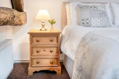 a bedroom with a bed and a nightstand with a lamp at Cottage 2, Old Farmhouse Mews in Braithwaite