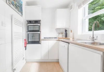 a white kitchen with white cabinets and a sink at Derwent Cottage in Keswick