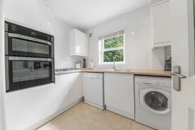 a white kitchen with a washer and dryer at Derwent Cottage in Keswick