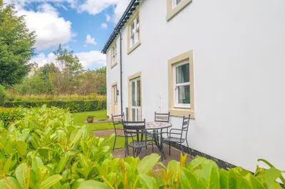 a patio with chairs and a table in front of a house at Derwent Cottage in Keswick