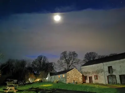 a moon over an old stone building at night at Rainors farm B&B in Gosforth