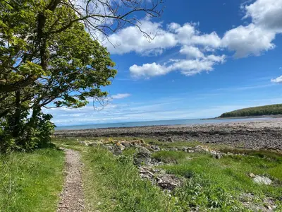 a dirt road leading to a beach with water at Islecroft House Bed & Breakfast in Isle of Whithorn