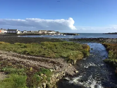 a stream of water on a beach next to the ocean at Islecroft House Bed & Breakfast in Isle of Whithorn