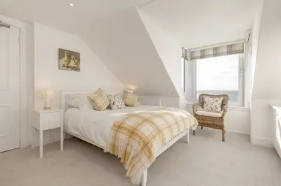 a bedroom with a bed and a chair and a window at Carlton House Portpatrick in Portpatrick