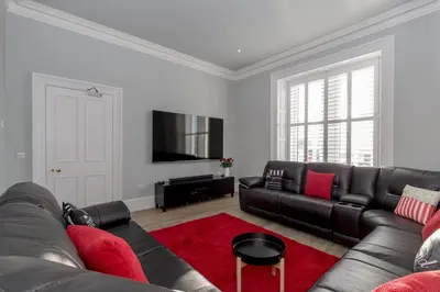 a living room with a black couch and a red rug at Carlton House Portpatrick in Portpatrick