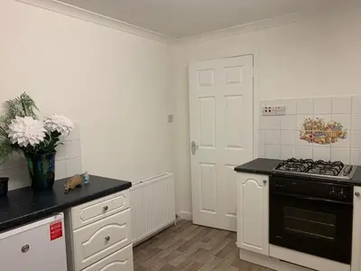 a kitchen with white cabinets and a black stove top oven at Dumfries Apartment in Dumfries