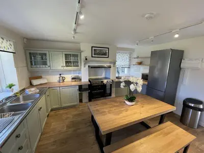 a kitchen with a wooden table and a counter top at Brandlehow HOT TUB HIRE AVAILABLE in Portinscale