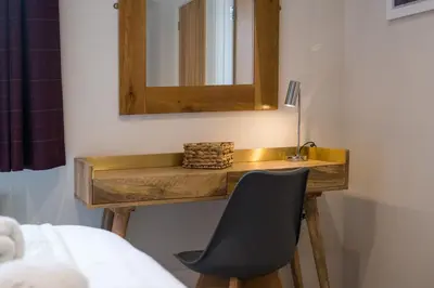 a bathroom with a wooden table with a mirror and a chair at Howe Keld 1 Ground floor in Keswick