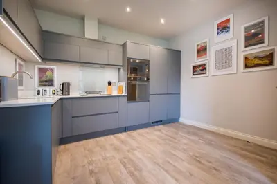 a kitchen with blue and white cabinets and wood floors at Howe Keld 3 Ground floor in Keswick