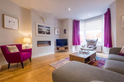 a living room with a couch and chairs and a tv at Howe Keld 2 Ground Floor in Keswick