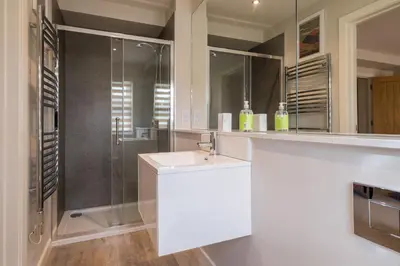 a white bathroom with a sink and a shower at Howe Keld 2 Ground Floor in Keswick