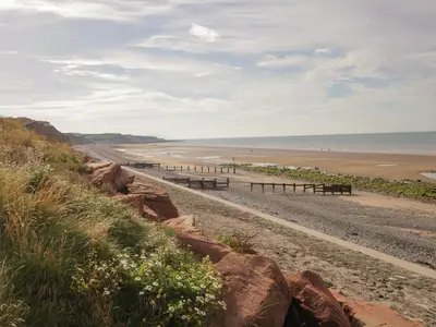 a row of benches on a beach next to the ocean at No 2 Waterloo Street in Cockermouth