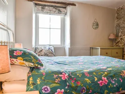 a bedroom with a bed with a floral bedspread at Pollywiggle Cottage in Keswick