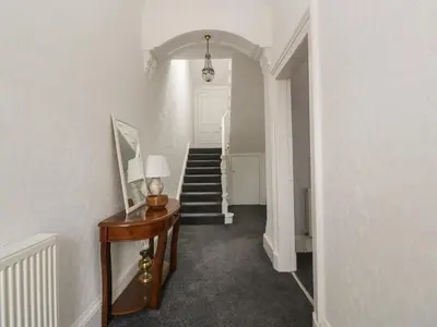 a hallway with a table with a lamp and stairs at Willowbank in Ayr
