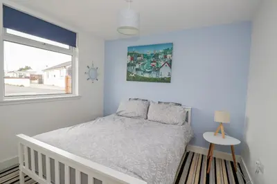 a white bedroom with a bed and a window at The Wigwam in Dumfries