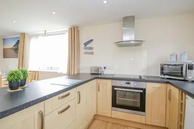a kitchen with wooden cabinets and a stove top oven at The Wigwam in Dumfries