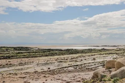a beach with rocks and the ocean in the background at The Wigwam in Dumfries