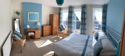 a bedroom with blue walls and a bed and a desk at Felltop Cottage in Keswick