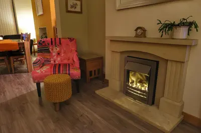 a living room with a fireplace and a chair at Felltop Cottage in Keswick